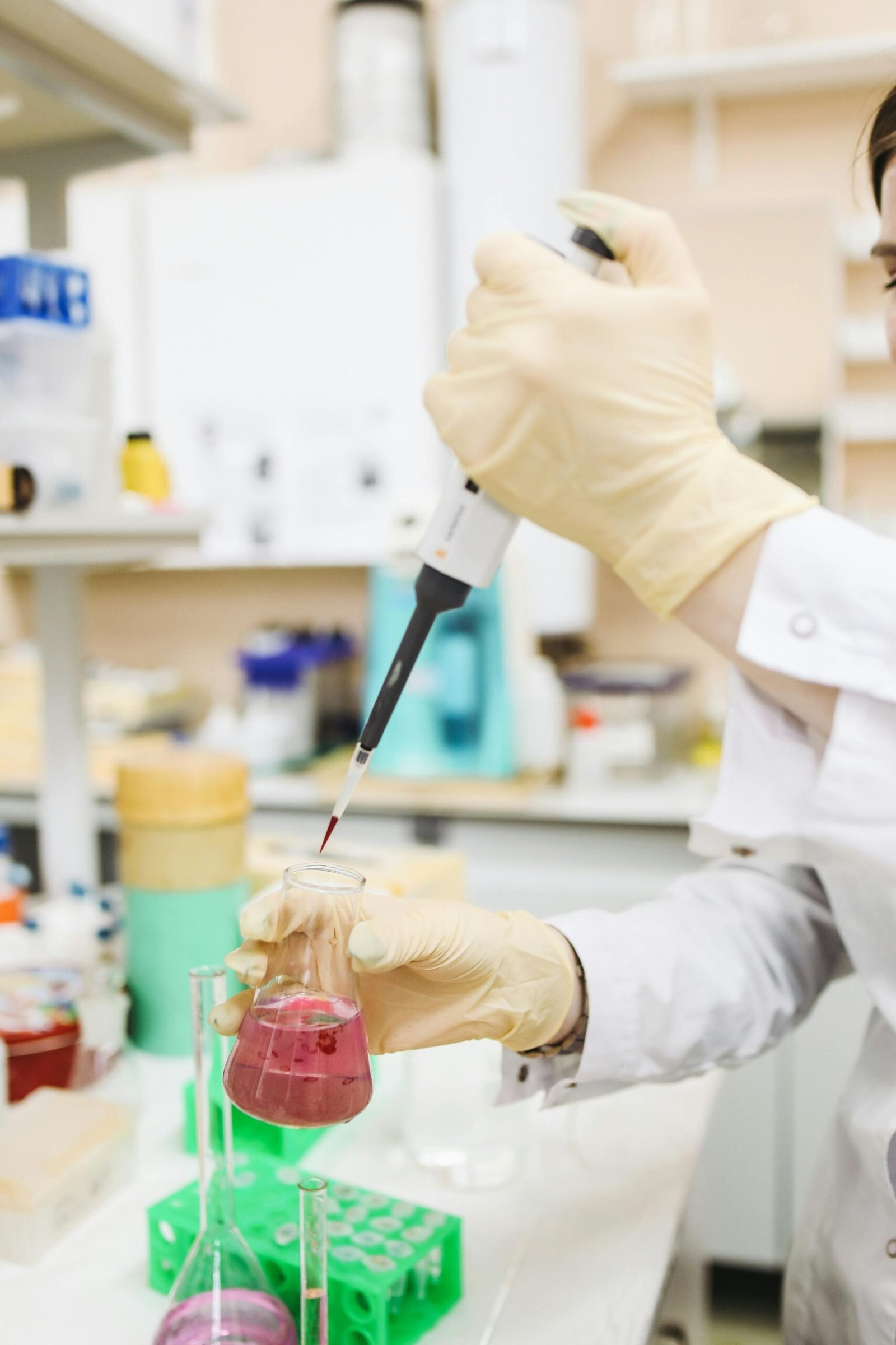 pexels-photo-3735786-3735786 A laboratory technician uses a pipette to transfer red liquid into a beaker in a science lab.