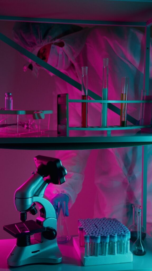 pexels-photo-8532867-8532867 A scientist in protective gear works in a neon-lit laboratory with test tubes and a microscope.